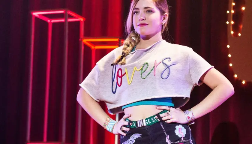 Młoda dziewczyna z warkoczem, w crop topie z napisem "lovers", pewnie pozuje na scenie. To część obsady "Go! Żyj po swojemu".