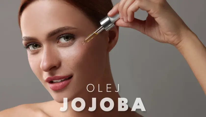 Kobieta aplikuje kroplę olejku jojoba na twarz, by nadać jej blask.
