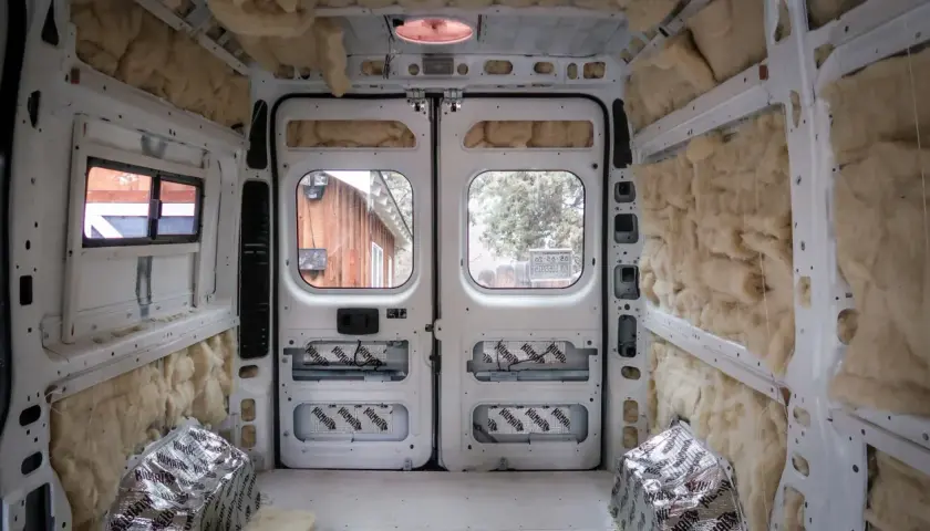 L'isolation d'un camping-car en cours, murs et plafond recouverts de laine de roche et de feuilles d'aluminium.