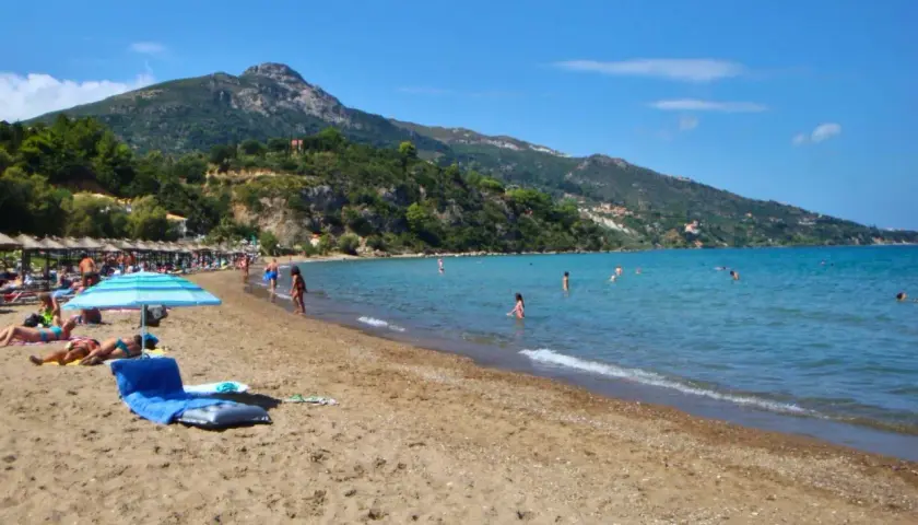 Słoneczna plaża na Zakynthos w czerwcu. Ludzie kąpią się w turkusowym morzu, opalają pod parasolami. Idealna pogoda na wakacje.