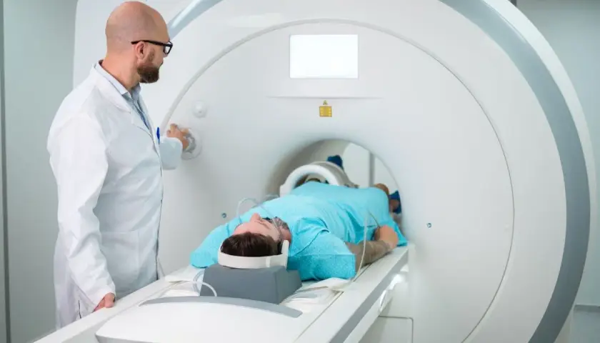Lekarz przygotowuje pacjenta do badania rezonansem magnetycznym. Pacjent leży w aparacie, gotowy na test apleya.