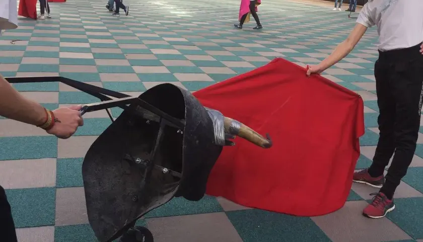 Jóvenes aprenden a torear con un capote y un toro de utilería.