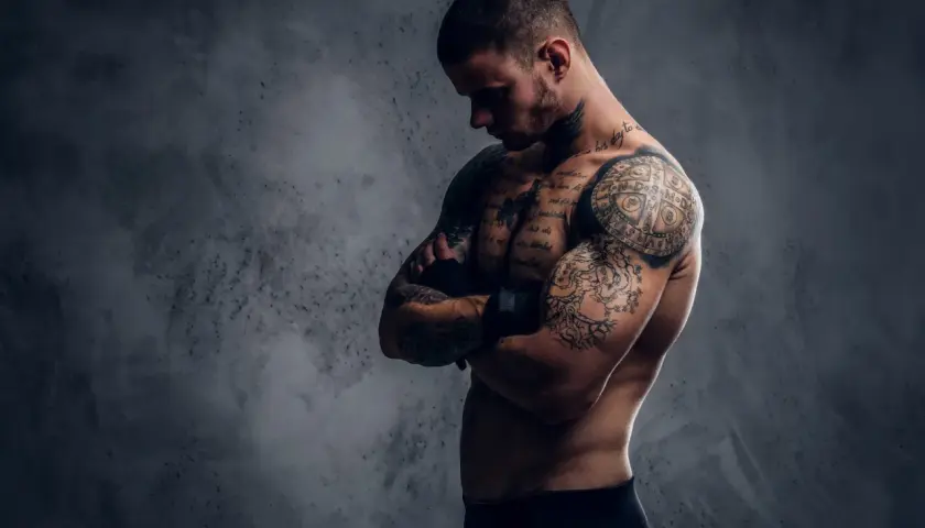 Mężczyzna z licznymi tatuażami na ciele, które tworzą jego drugą skórę po tatuazu.