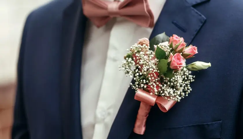 Elegancka muszka do granatowego garnituru, ozdobiona bukiecikiem różowych różyczek i gipsówki.