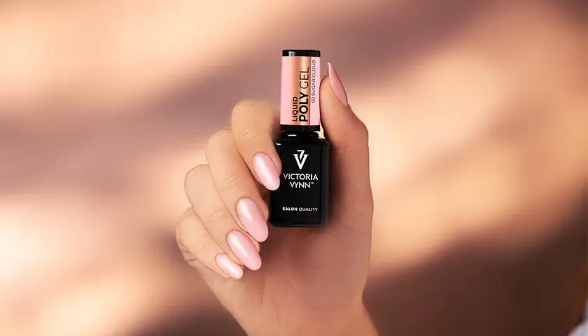 Dłoń z różowymi paznokciami trzyma buteleczkę Liquid Poly Gel Victoria Vynn. To produkt do stylizacji paznokci.
