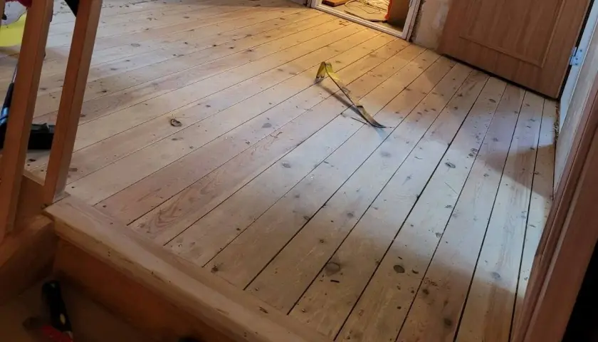 Ett rum med nylagt råspont golv. Ett verktyg ligger på golvet, redo för nästa steg i renoveringen.