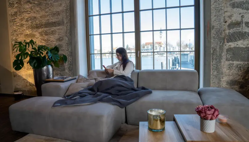 Femme en bonne position assise canapé, profitant de son téléphone avec une vue sur l'eau.
