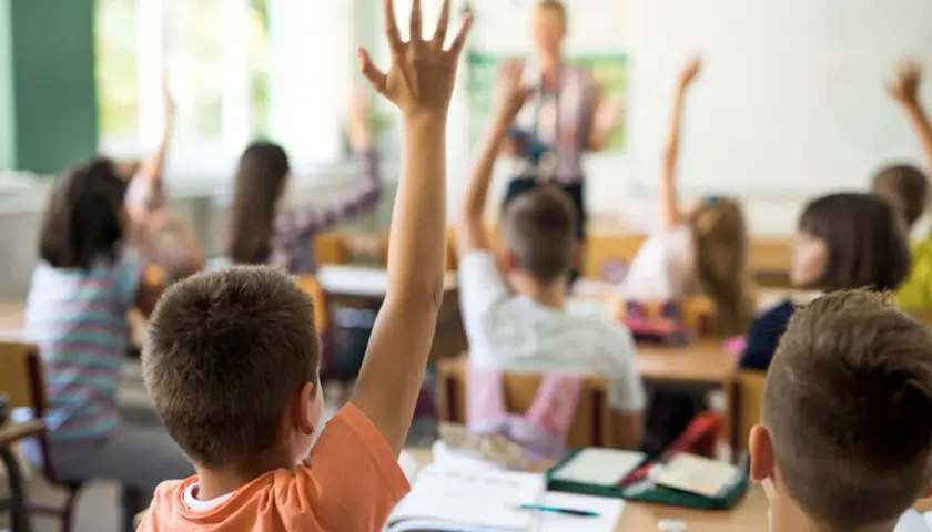 Erste Klasse: Kinder melden sich eifrig, um Fragen zu beantworten. Hier lernt man das ABC und die ersten Zahlen.