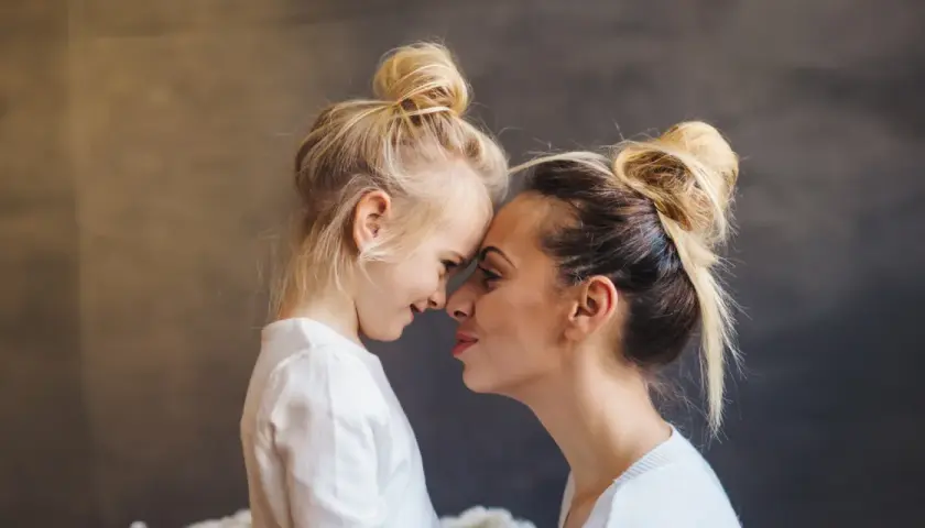 Blondynka z córką, dziecko z poprzedniego związku, czule dotykają się noskami. Nowy partner wkracza w ich życie.