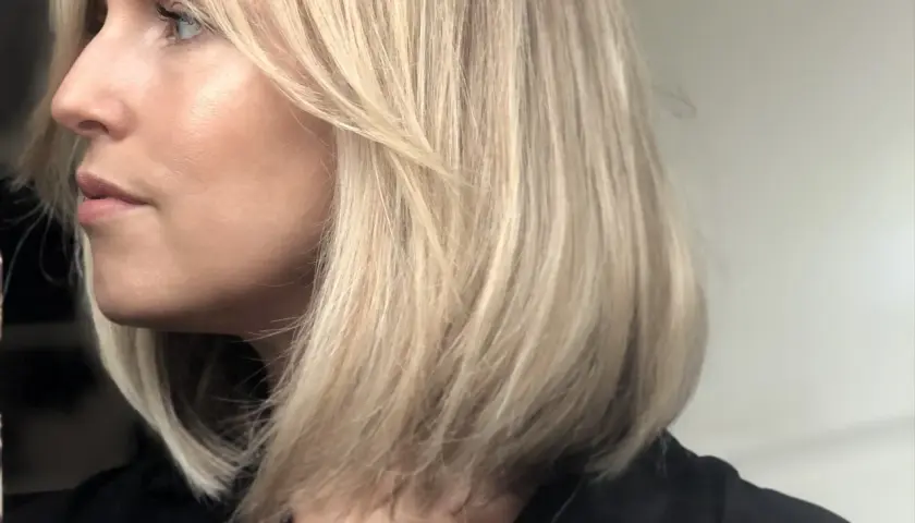 En kvinna med blont hår i en lobklippning, med en naturlig sminkning som framhäver hennes ansiktsdrag. Perfekt för smink tips.