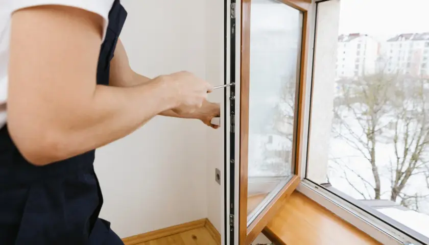 Installazione di infissi bicolore: un tecnico con tuta blu avvita una parte del telaio. Opinioni positive per un design moderno.