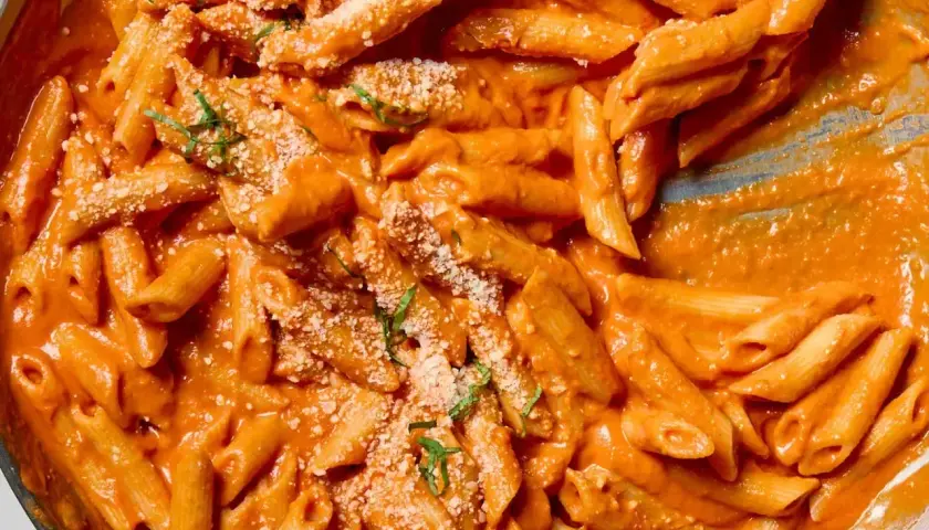Penne alla vodka w kremowym, pomarańczowym sosie, posypane parmezanem i bazylią.