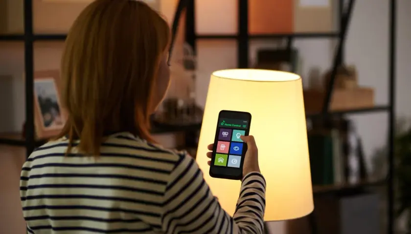 Kobieta steruje domem przez aplikację na telefonie. To smart life po polsku, wygoda i nowoczesność w zasięgu ręki.