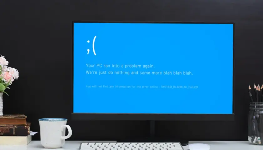 Smutna buźka na niebieskim ekranie komputera. "Your PC ran into a problem again." - klasyczny bluescreen.