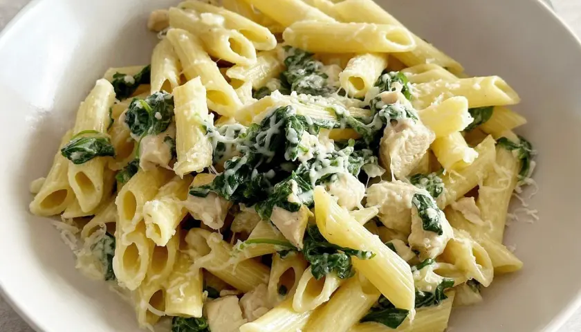 Penne z kurczakiem i szpinakiem w kremowym sosie, posypane parmezanem. Pyszne danie, które zadowoli każdego miłośnika makaronów.