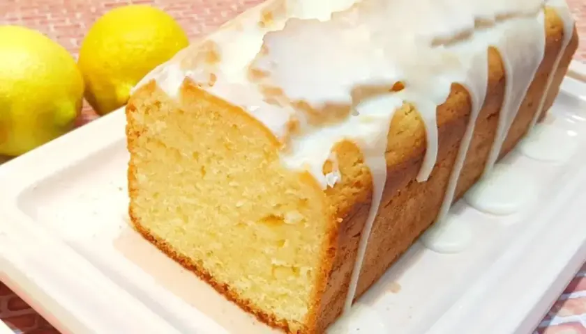 Budín de limón casero con glaseado blanco, acompañado de dos limones frescos. ¡Perfecto para la merienda!