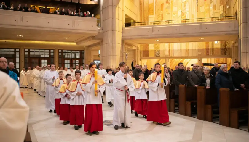 Procesja dzieci niosących świece w kościele. Dziś msza trwa dłużej, bo to uroczystość.