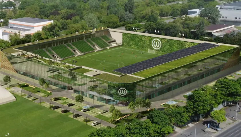 Nowoczesny stadion Warty Poznań z zielonymi dachami, panelem słonecznym i ścianą porośniętą roślinnością.