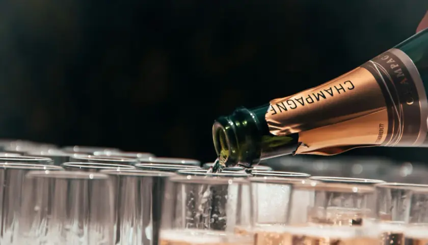 Une bouteille de champagne verse son contenu pétillant dans une rangée de flûtes. Ce type de champagne promet une célébration.