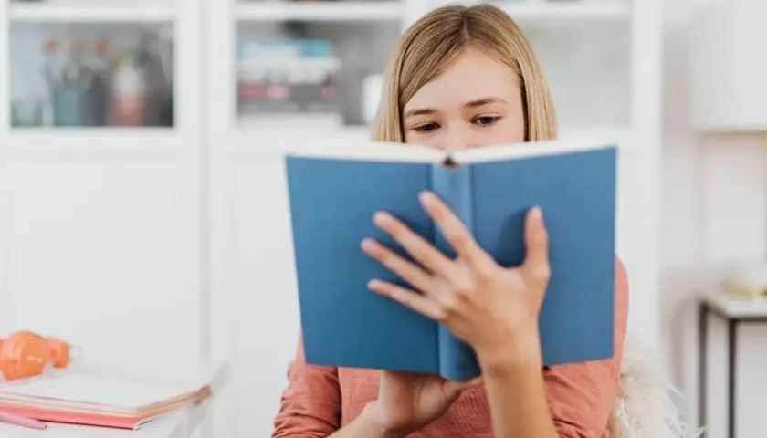 Dziewczynka pochłonięta lekturą, która wywołuje dreszczowiec. Jej oczy błyszczą, gdy śledzi kolejne zwroty akcji.