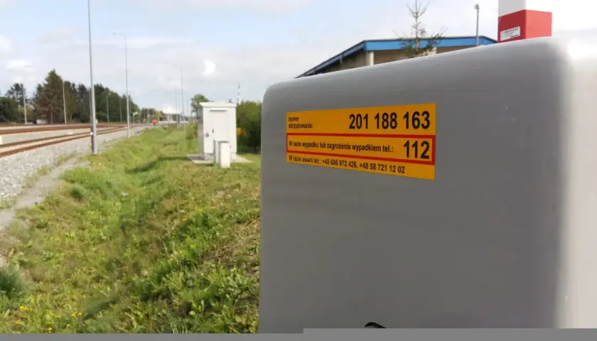 Żółta naklejka plk. z numerem skrzyżowania 201 188 163 i numerem alarmowym 112.