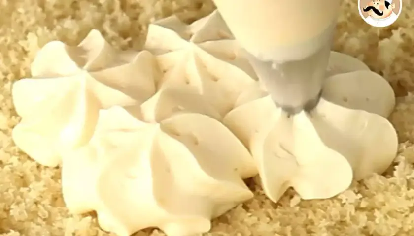 Une poche à douille dépose de jolies rosaces de crème diplomate sur un gâteau.