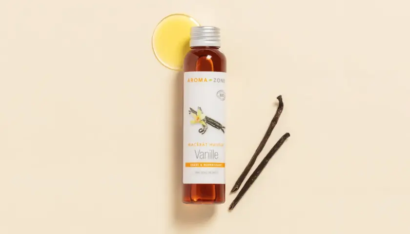 Flacon d'huile de vanille Aroma-Zone, avec des gousses de vanille et une goutte d'huile dorée.