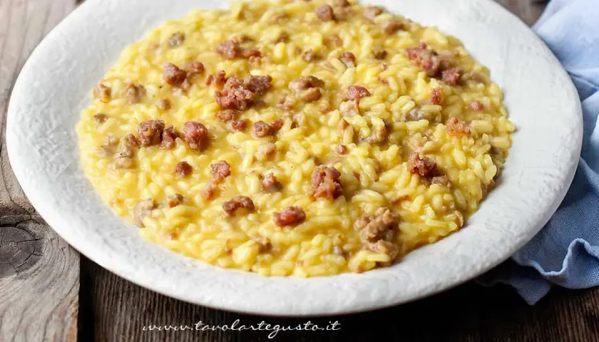 Un cremoso risotto con salsiccia, servito su un piatto bianco, pronto per essere gustato.