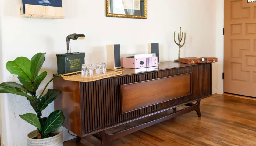 A mid-century modern wood console with a record player, speakers, and a fiddle leaf fig plant.