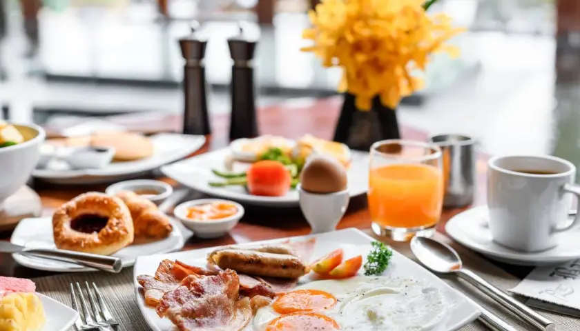 Un copieux petit déjeuner continental ou américain avec œufs, bacon, saucisses, viennoiseries, jus d'orange et café.