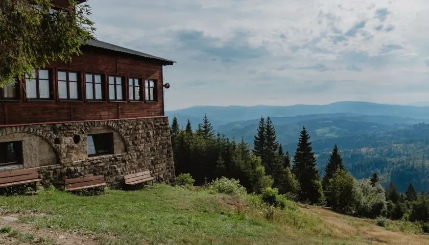 Drewniany schron na zboczu, skąd rozpościera się widok na Beskidy. Idealne miejsce na odpoczynek po wędrówce szlakami Wisły.