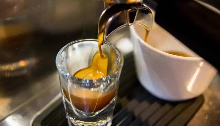 Gorący strumień kawy spływa do szklanki, tworząc idealne espresso. To właśnie taka kawa jest najlepsza!