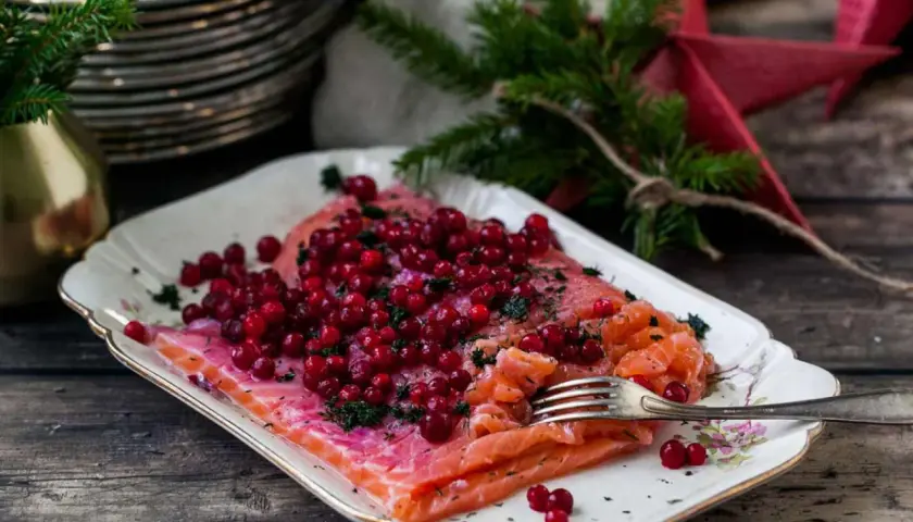 Apelsingravad lax med lingon och dill på ett vackert fat, redo för julbordet.