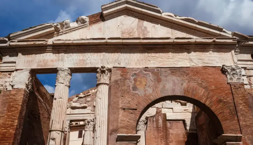 Antico portico d'Ottavia a Roma, con iscrizioni latine e resti di affreschi su mattoni antichi.