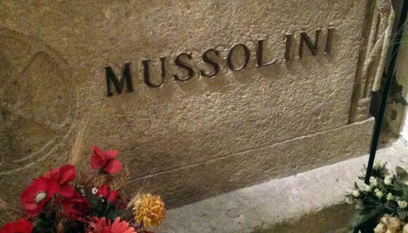 Grabstein mit der Inschrift "MUSSOLINI" und Blumen. Hier ist das Grab von Mussolini.