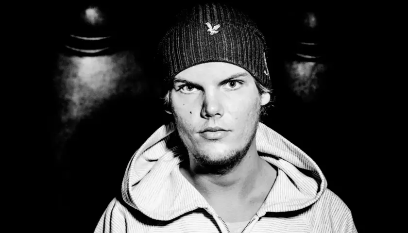 Avicii, młody mężczyzna w czapce z daszkiem i bluzie z kapturem, patrzy prosto w obiektyw.