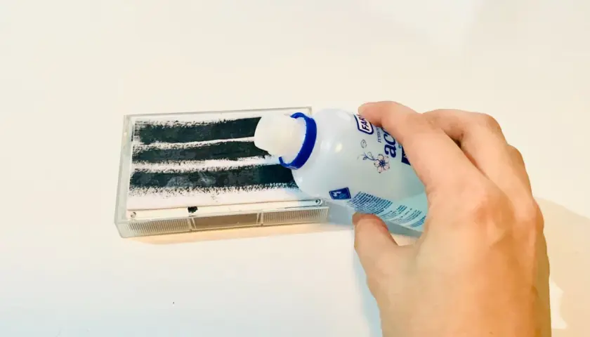 Mano versa liquido da flacone su nastro adesivo per rimuovere colla adesivi.