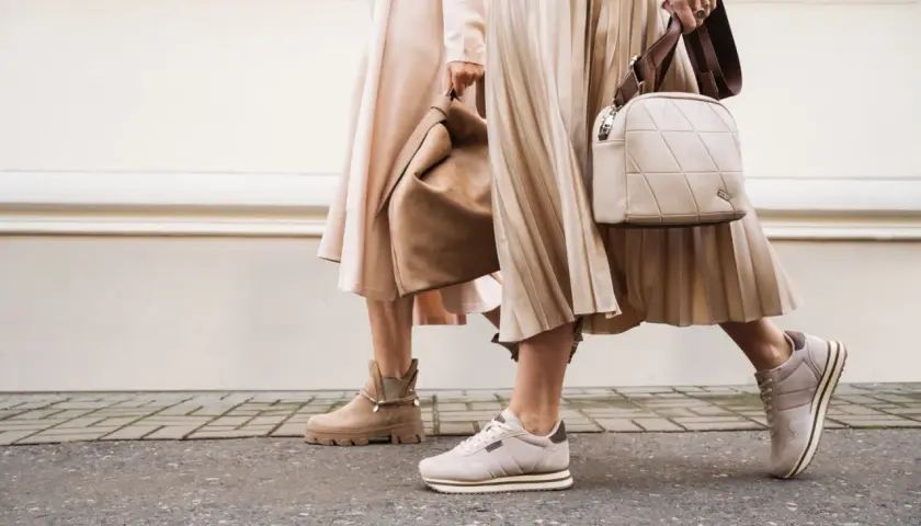 Dwie kobiety w beżowych sukienkach i butach. Jedna ma botki, druga sneakersy. Idealne pytanie: jakie buty do rajstop?