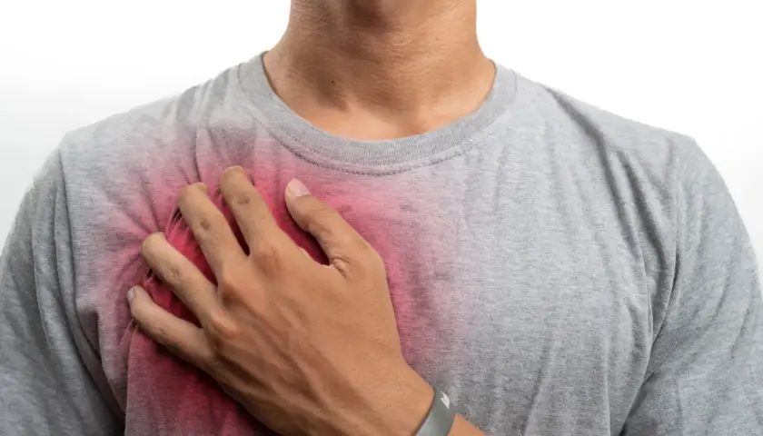 Uomo con mano sul petto, evidenziando un'area arrossata che suggerisce prurito al petto uomo.