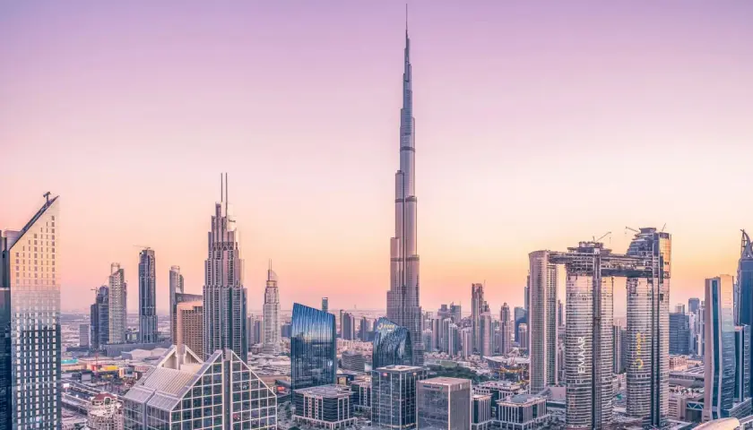 Widok panoramy Dubaju z Burdż Chalifą na pierwszym planie, w blasku zachodzącego słońca.