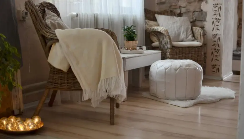 Gemütliche **hygge einrichtung**: Korbstühle, ein weicher Überwurf und ein weißer Pouf laden zum Entspannen ein.