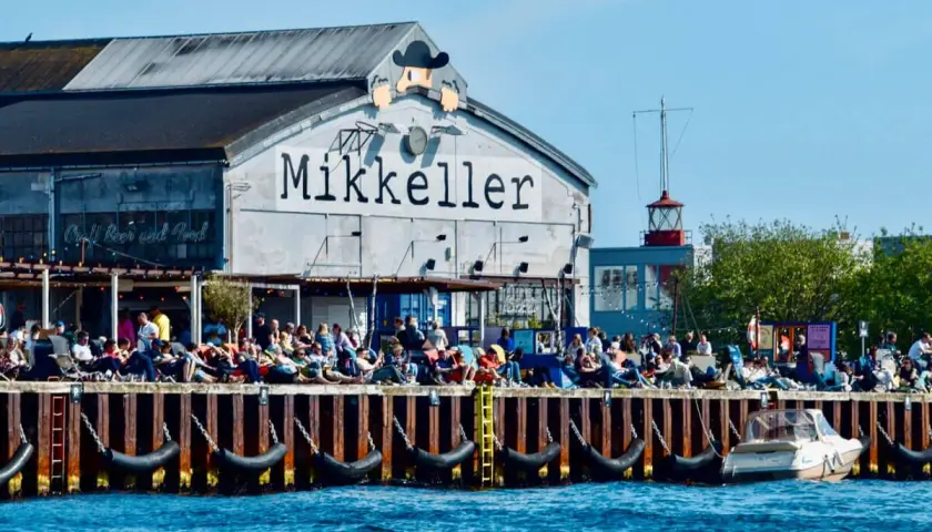 Menschen genießen das Kopenhagen Essen und Craft Beer am Kai vor dem Mikkeller Gebäude.