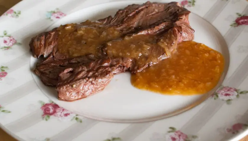 Un plat de viande tendre nappé d'une sauce onctueuse à l'échalote, servi sur une assiette à motifs floraux.