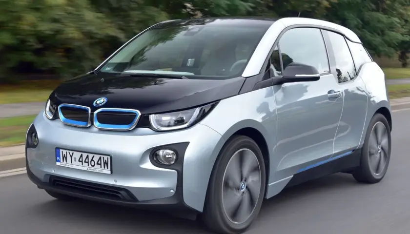 Srebrno-czarny BMW i3, elektryczny samochód, jedzie po drodze.