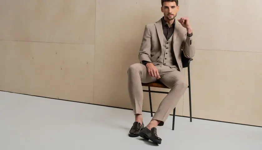 Elegancki mężczyzna w garniturze i kamizelce prezentuje, co to za buty: stylowe, ciemne loafersy.