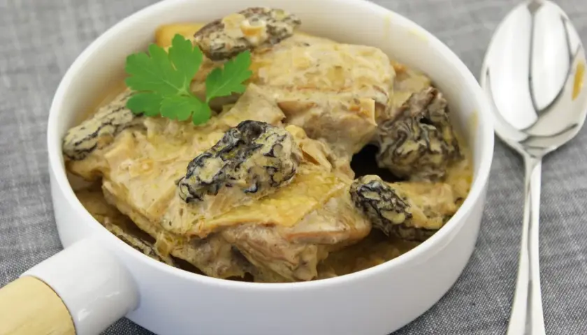 Un plat de poularde crémeuse aux morilles, garni de persil. Parfait pour savoir que servir avec une poularde au vin jaune.