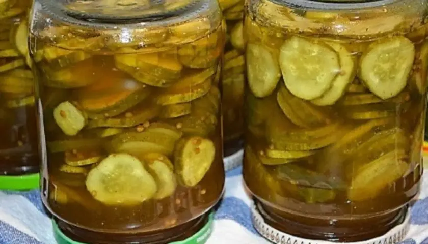 Słoiki pełne plasterków ogórków w zalewie z przyprawami, gotowe do podania jako dodatek do dań. Te ogórki w curry z pewnością dodadzą smaku!