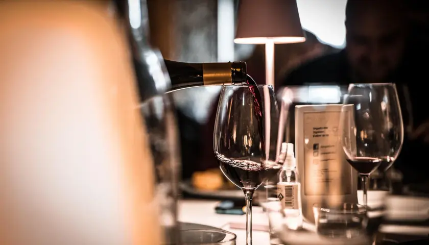 Verre de vin rouge servi dans un bar, ambiance feutrée.