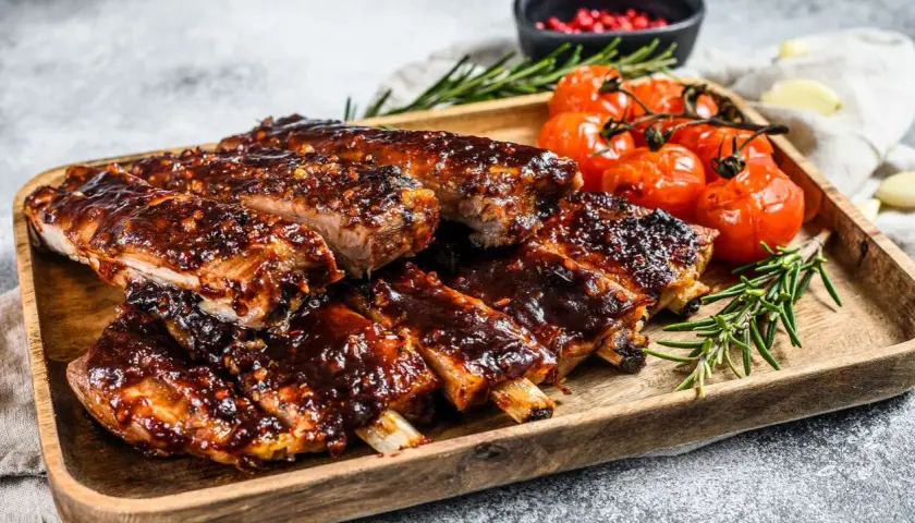 Soczyste żeberka w sosie BBQ, podane z pieczonymi pomidorkami i rozmarynem. Idealne na obiad lub grilla.