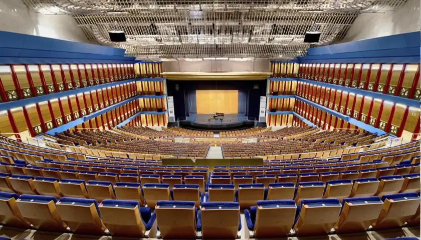 El **palacio de festivales** luce vacío, con sus butacas azules y doradas listas para recibir al público. Un piano espera en el escenario.